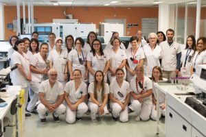 Toute l'équipe du nouveau centre de prélèvements. On y voit une bonne vingtaine de personnes en blouses en tenues blanches, au sein de l'hôpital. Elles sont regroupées pour la photo et sourient. Les personnes au premier rang sont à genoux ou assises.
